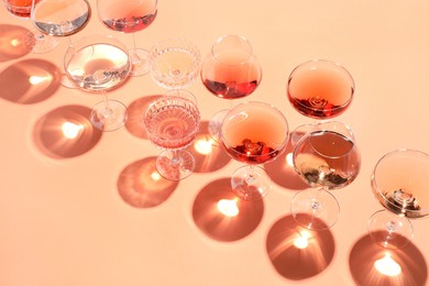 Tasty rose wine in glasses on coral color background