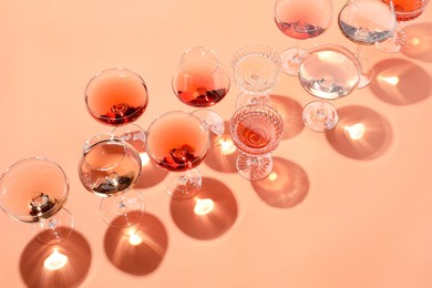 Tasty rose wine in glasses on coral color background