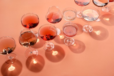 Tasty rose wine in glasses on coral color background