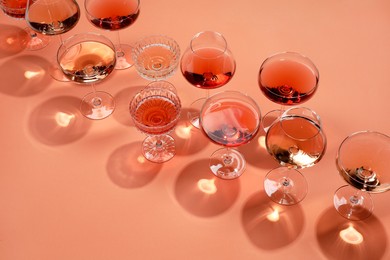 Photo of Tasty rose wine in glasses on coral color background