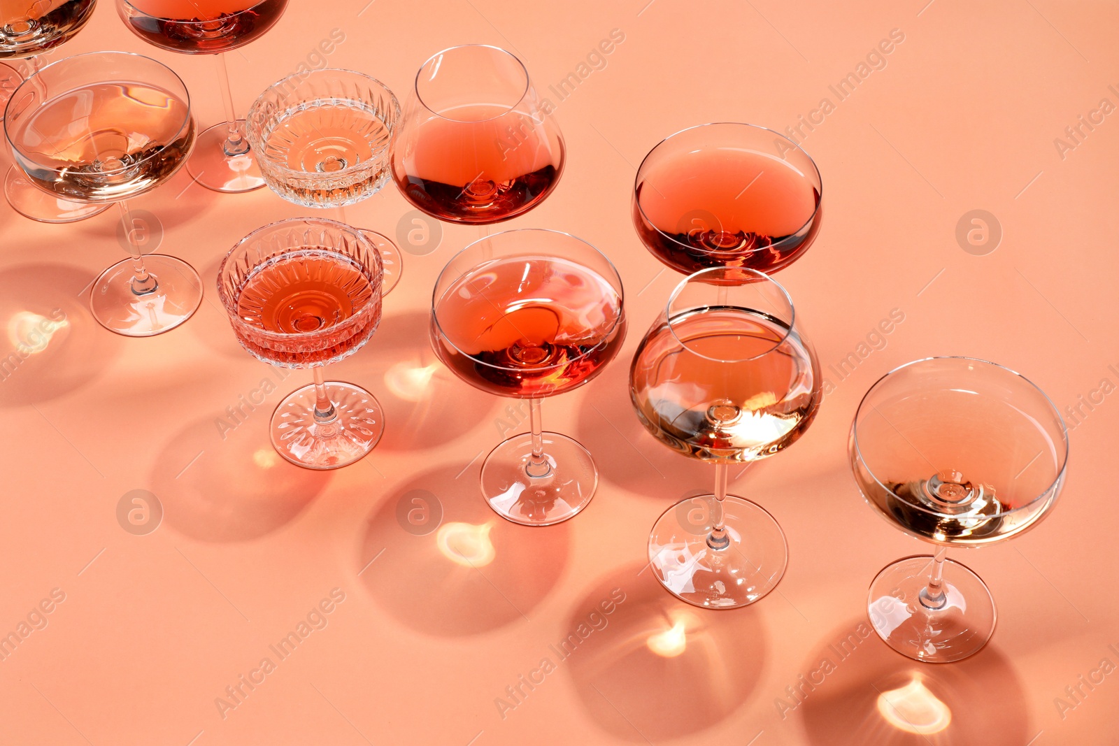 Photo of Tasty rose wine in glasses on coral color background