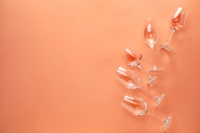 Photo of Wineglasses on coral color background, flat lay. Space for text