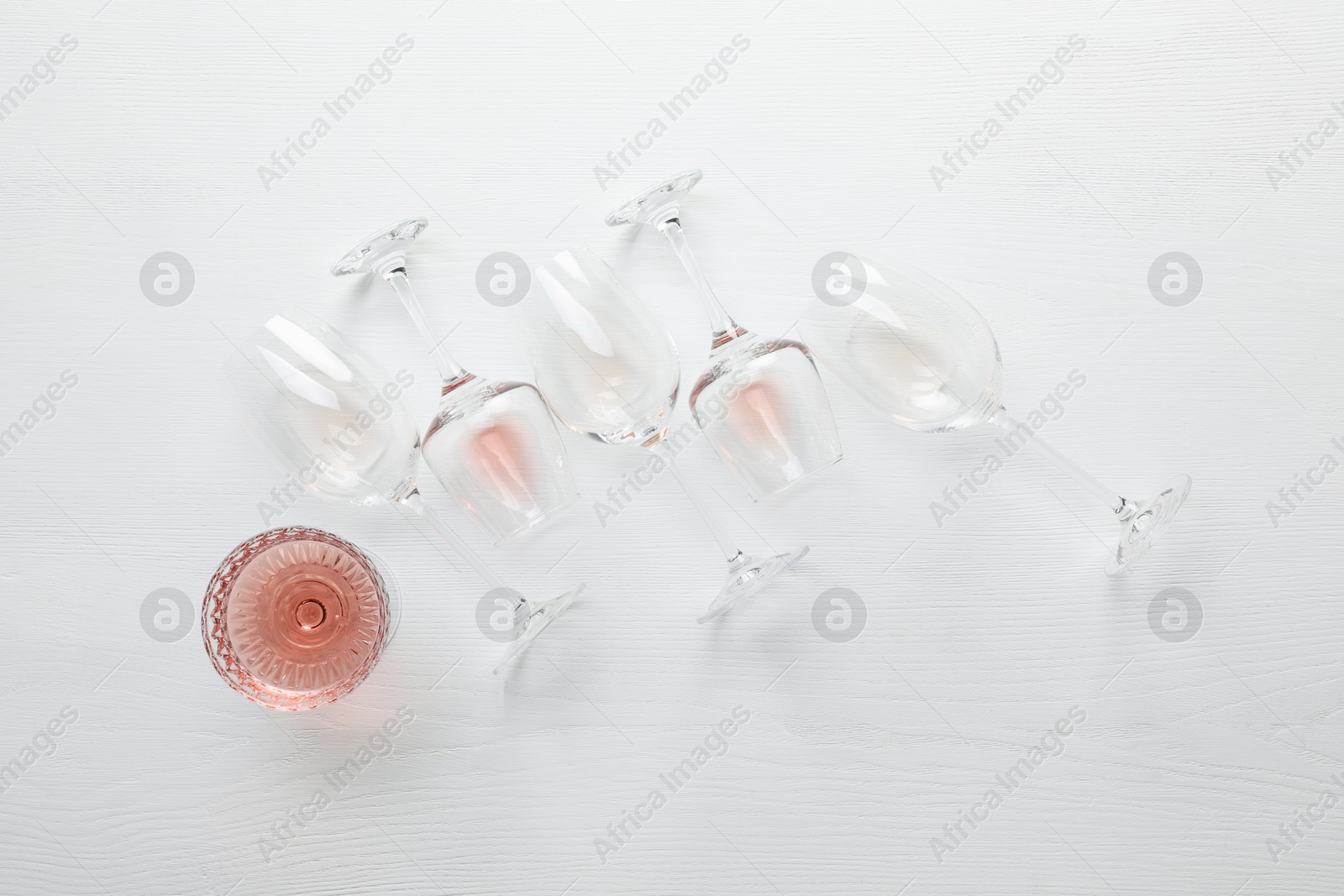 Photo of Tasty rose wine in glasses on white wooden table, flat lay