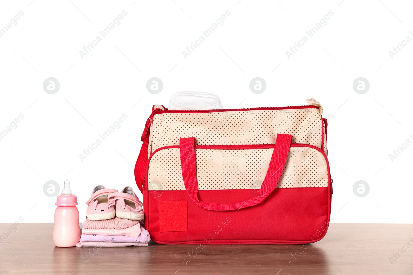 Photo of Mother's bag with baby's stuff on wooden table against white background