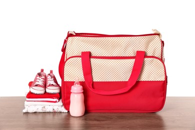 Mother's bag with baby's stuff on wooden table against white background