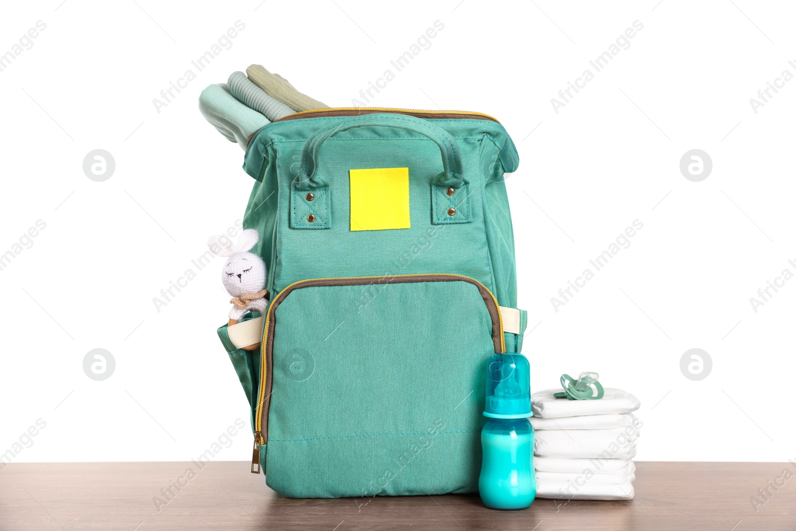 Photo of Mother's bag with baby's stuff on wooden table against white background