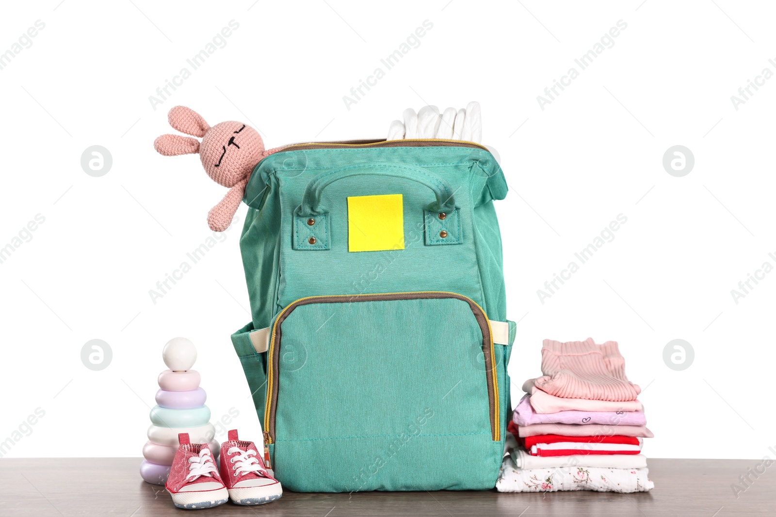 Photo of Mother's bag with baby's stuff on wooden table against white background