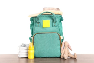 Photo of Mother's bag with baby's stuff on wooden table against white background