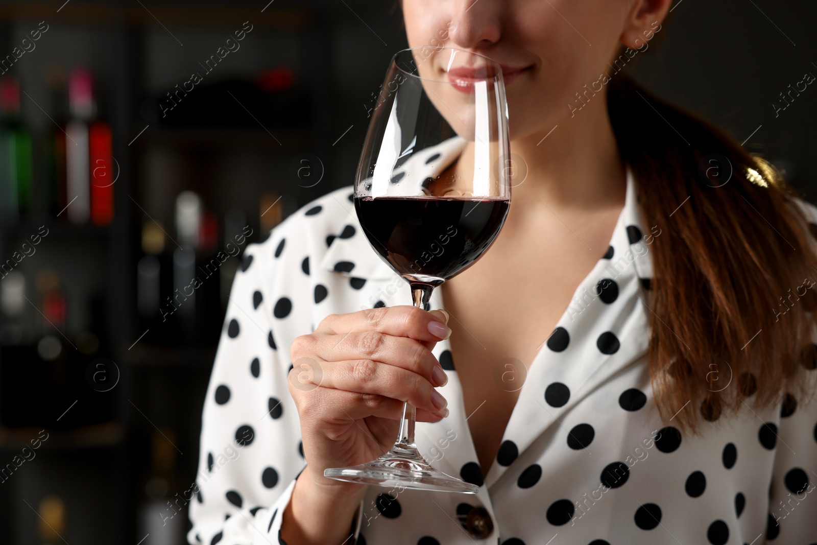 Photo of Professional sommelier tasting red wine in glass indoors, closeup