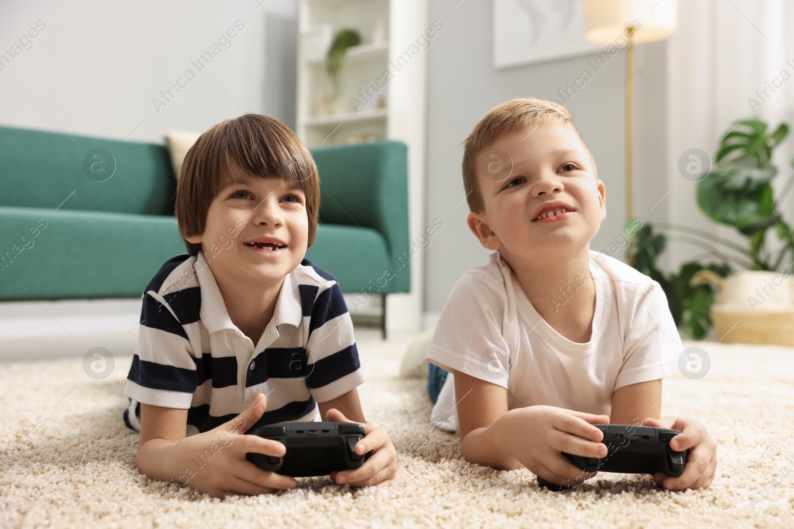 Photo of Cute brothers playing video game on floor at home