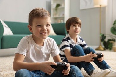 Photo of Cute brothers playing video game on floor at home