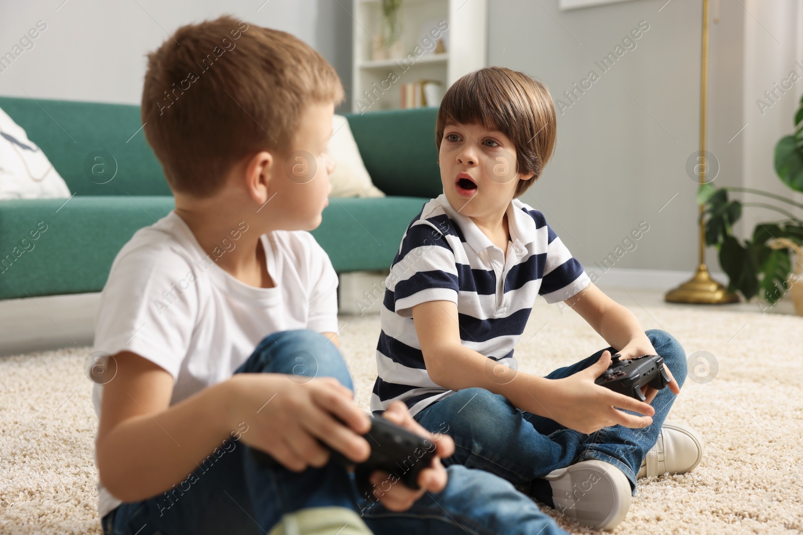 Photo of Cute brothers playing video game on floor at home