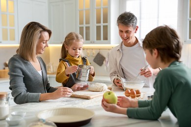 Photo of Happy family making dough at table in kitchen