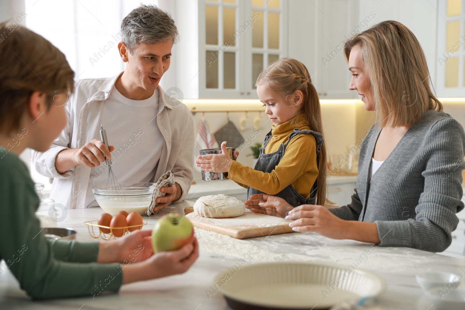 Photo of Happy family making dough at table in kitchen