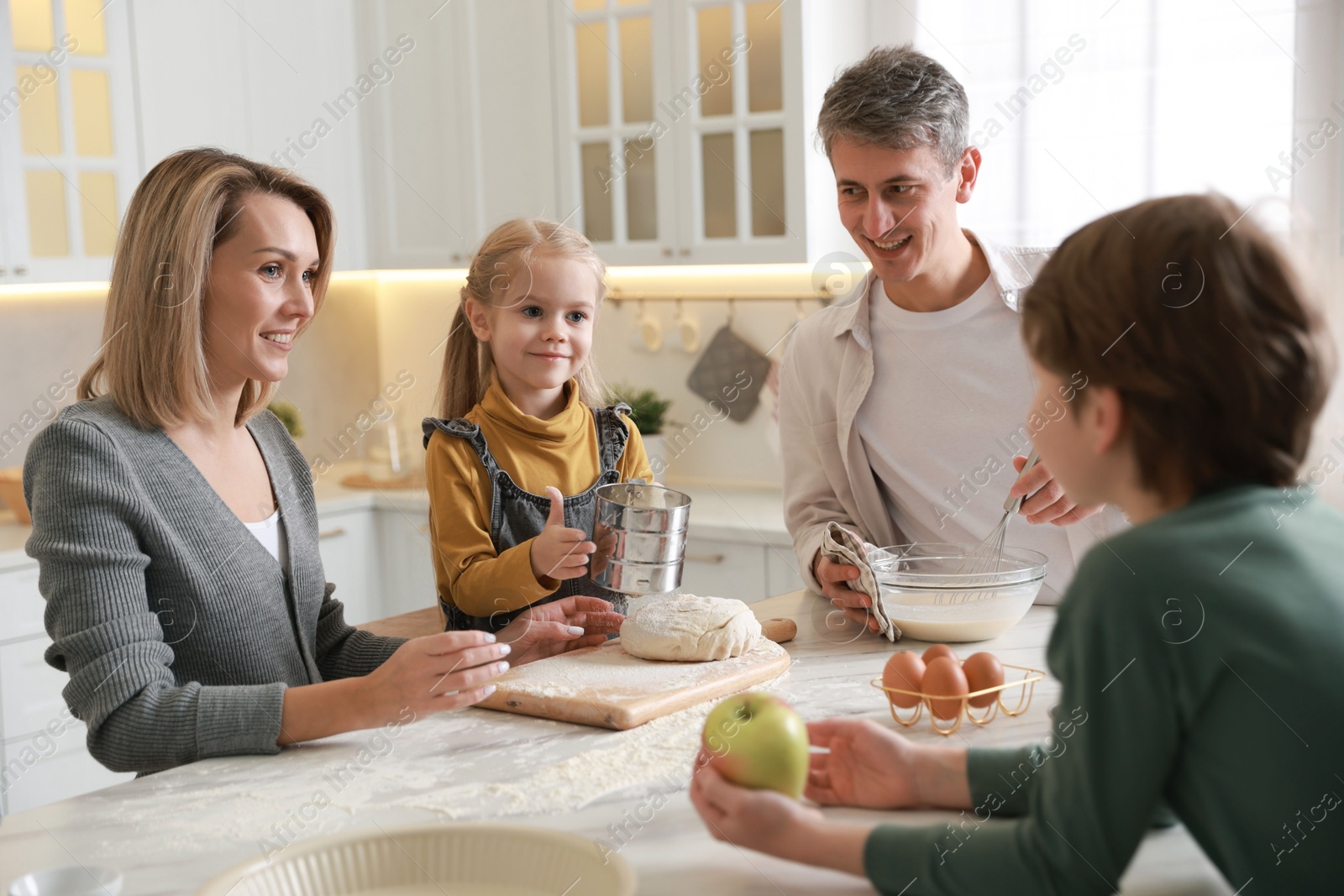 Photo of Happy family making dough at table in kitchen