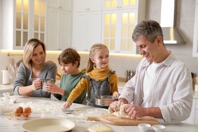 Photo of Happy family making dough at white marble table in kitchen