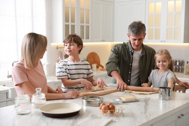 Photo of Happy family making dough at white marble table in kitchen