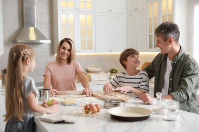 Photo of Happy family making dough at white marble table in kitchen