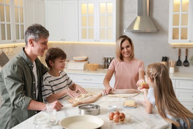 Photo of Happy family making dough at white marble table in kitchen