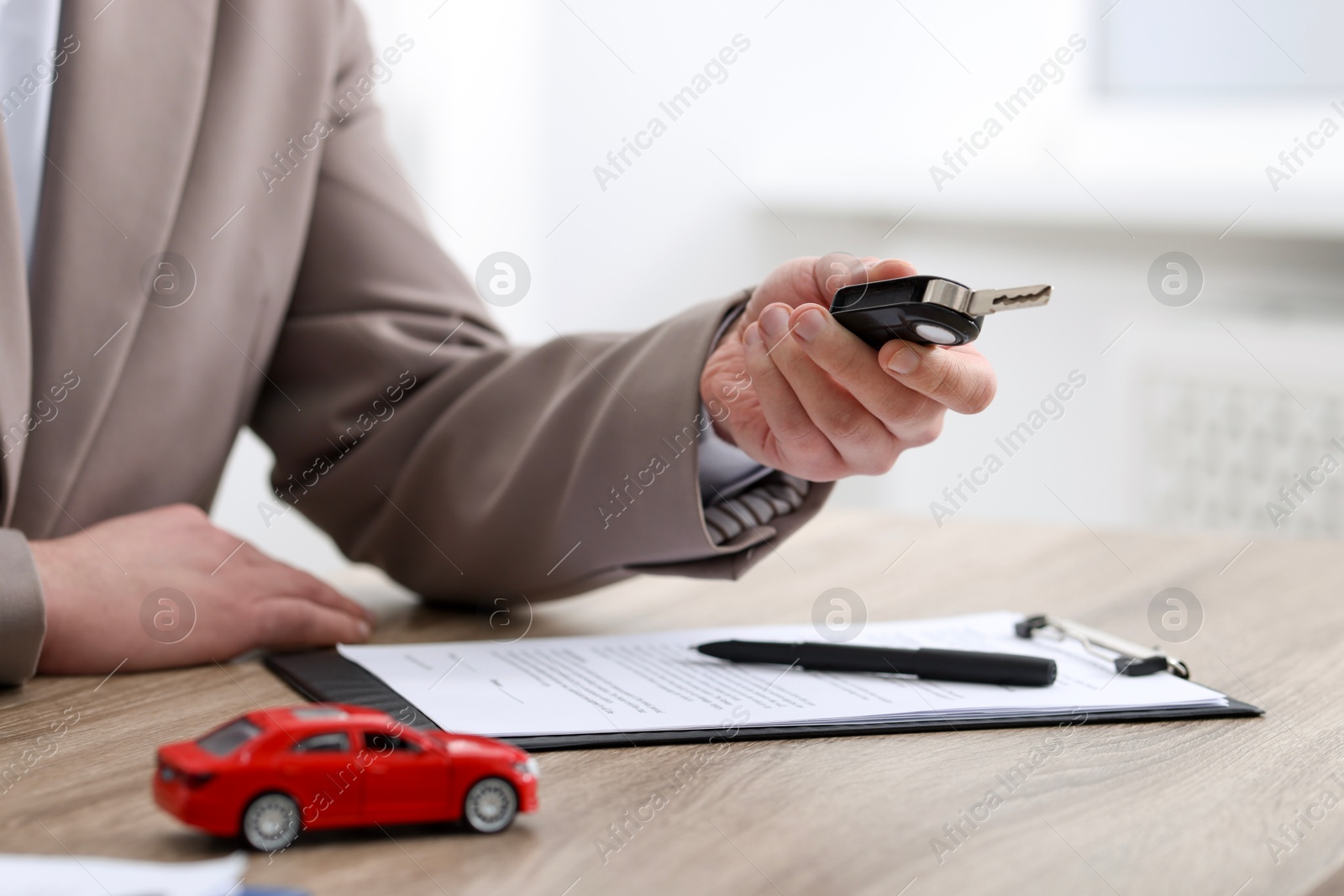 Photo of Man with car key at table indoors, selective focus. Buying auto