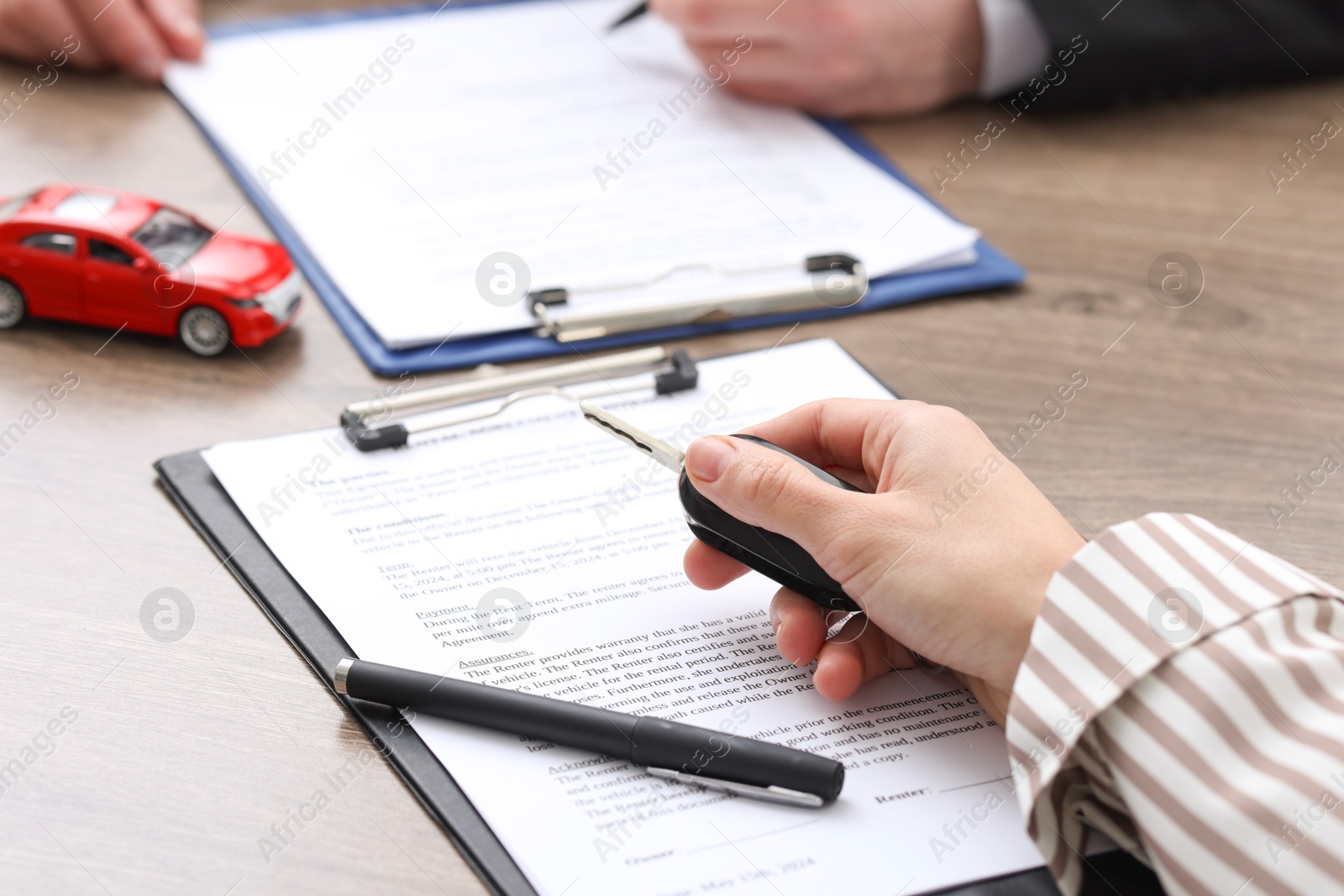 Photo of Salesman with key and documents at wooden table in office, closeup. Buying auto