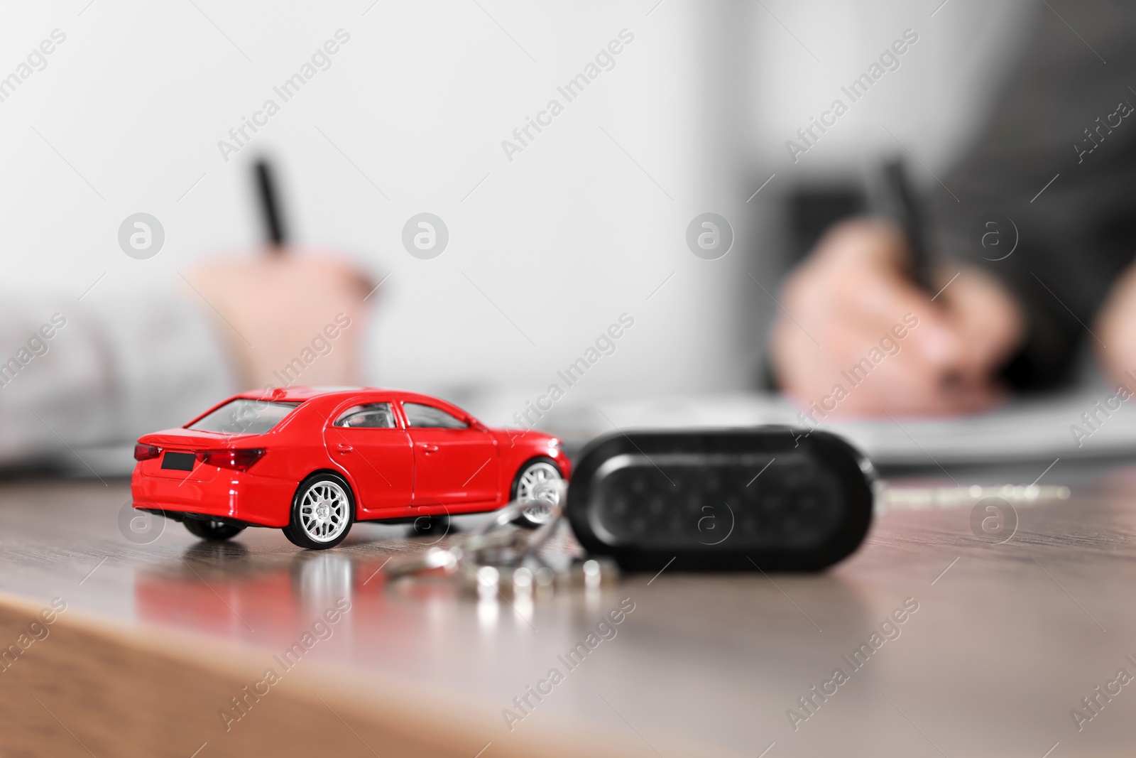 Photo of Buying auto. Car model and key on wooden table, selective focus