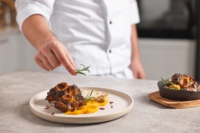 Photo of Professional chef serving dish at table indoors, closeup