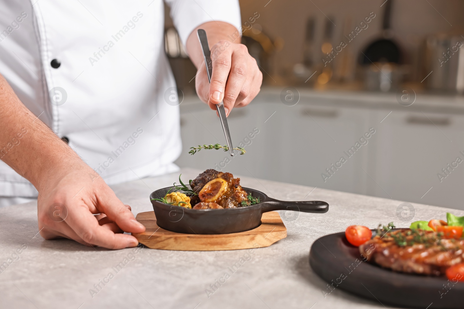 Photo of Professional chef serving dish at table indoors, closeup