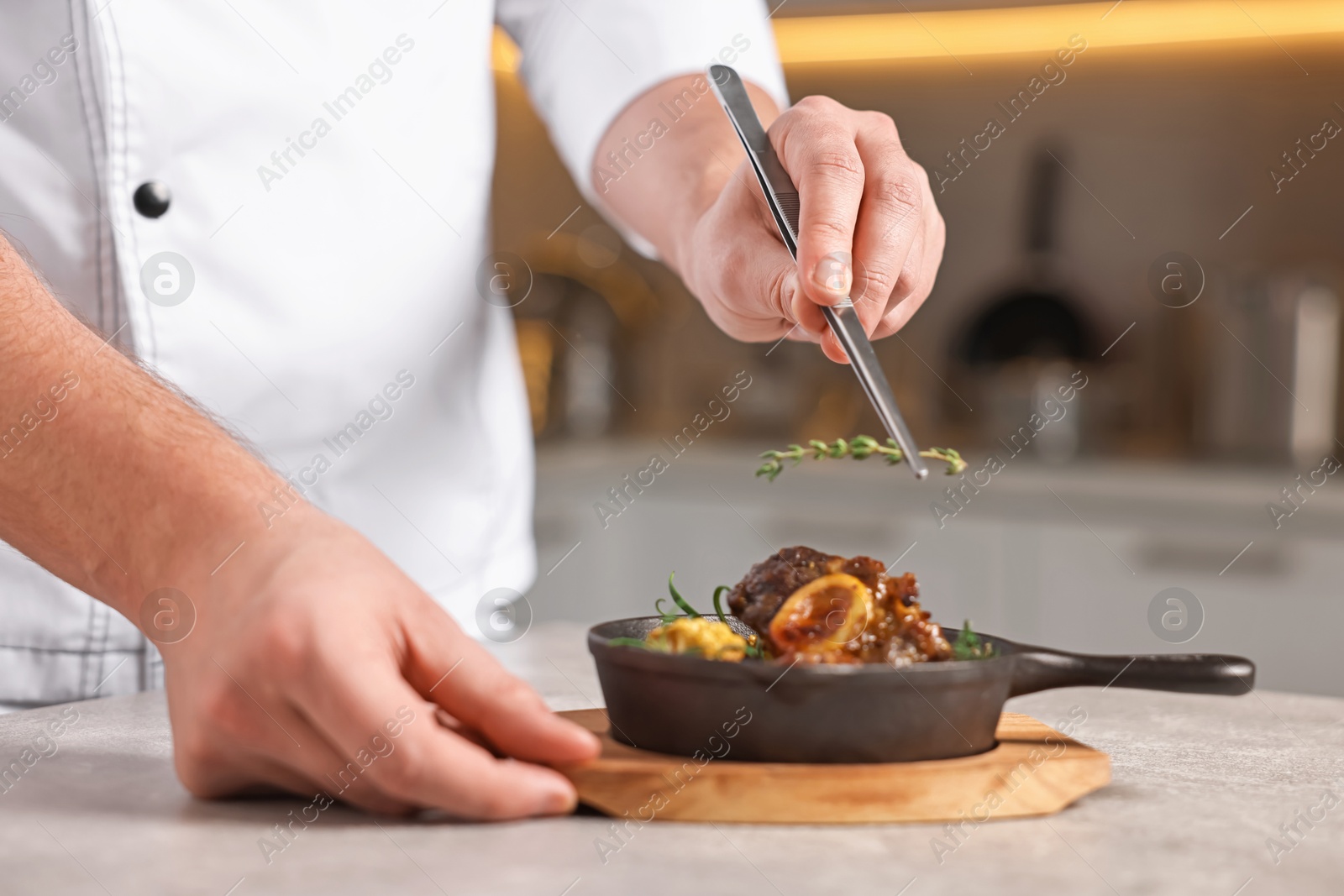 Photo of Professional chef serving dish at table indoors, closeup