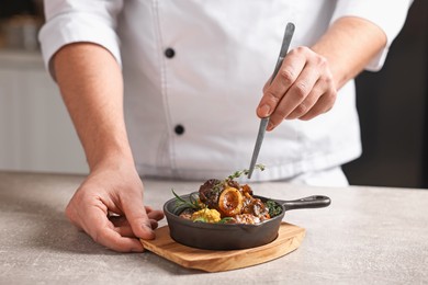 Photo of Professional chef serving dish at table indoors, closeup