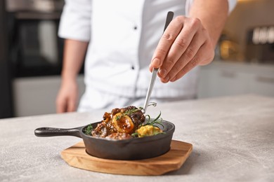 Photo of Professional chef serving dish at table indoors, closeup