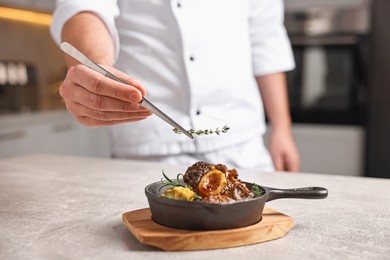 Photo of Professional chef serving dish at table indoors, closeup