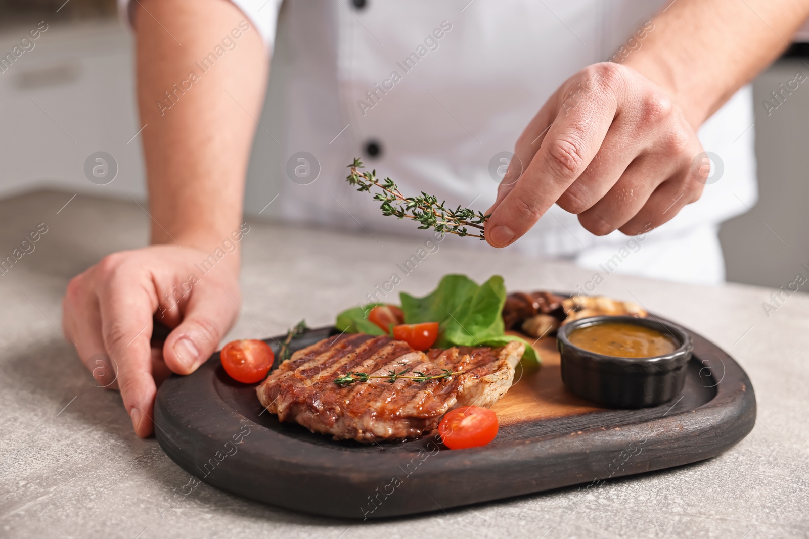 Photo of Professional chef serving dish at table indoors, closeup