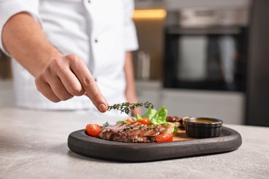 Photo of Professional chef serving dish at table indoors, closeup