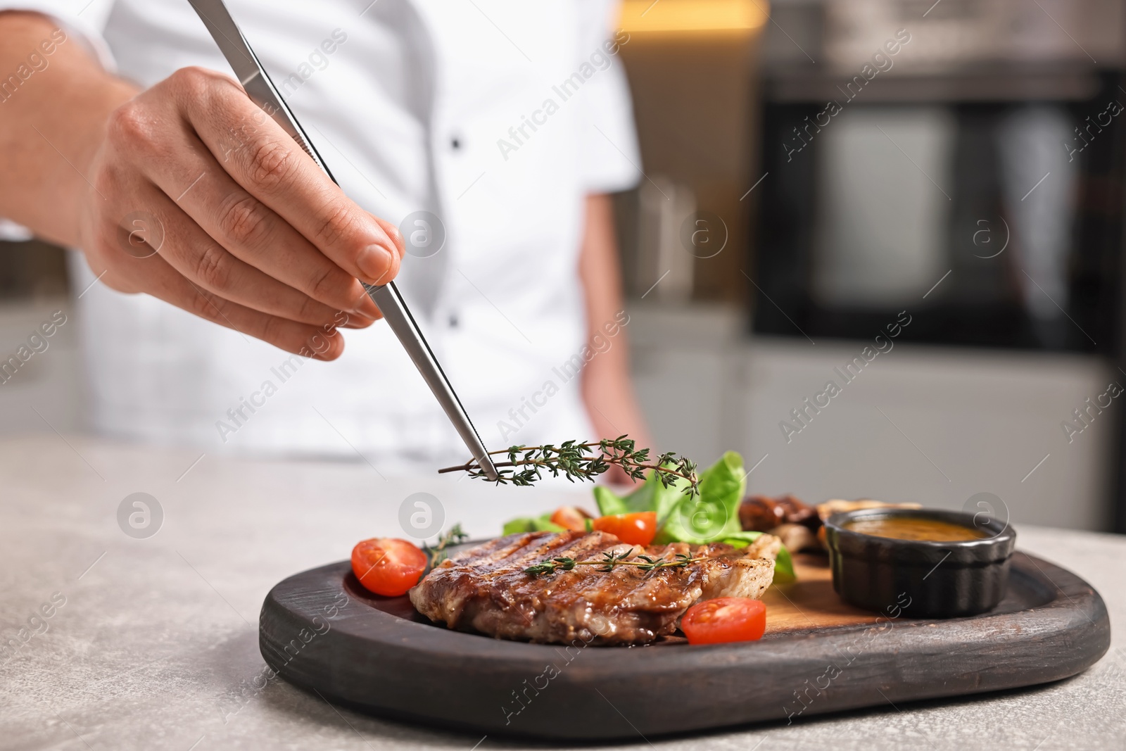 Photo of Professional chef serving dish at table indoors, closeup