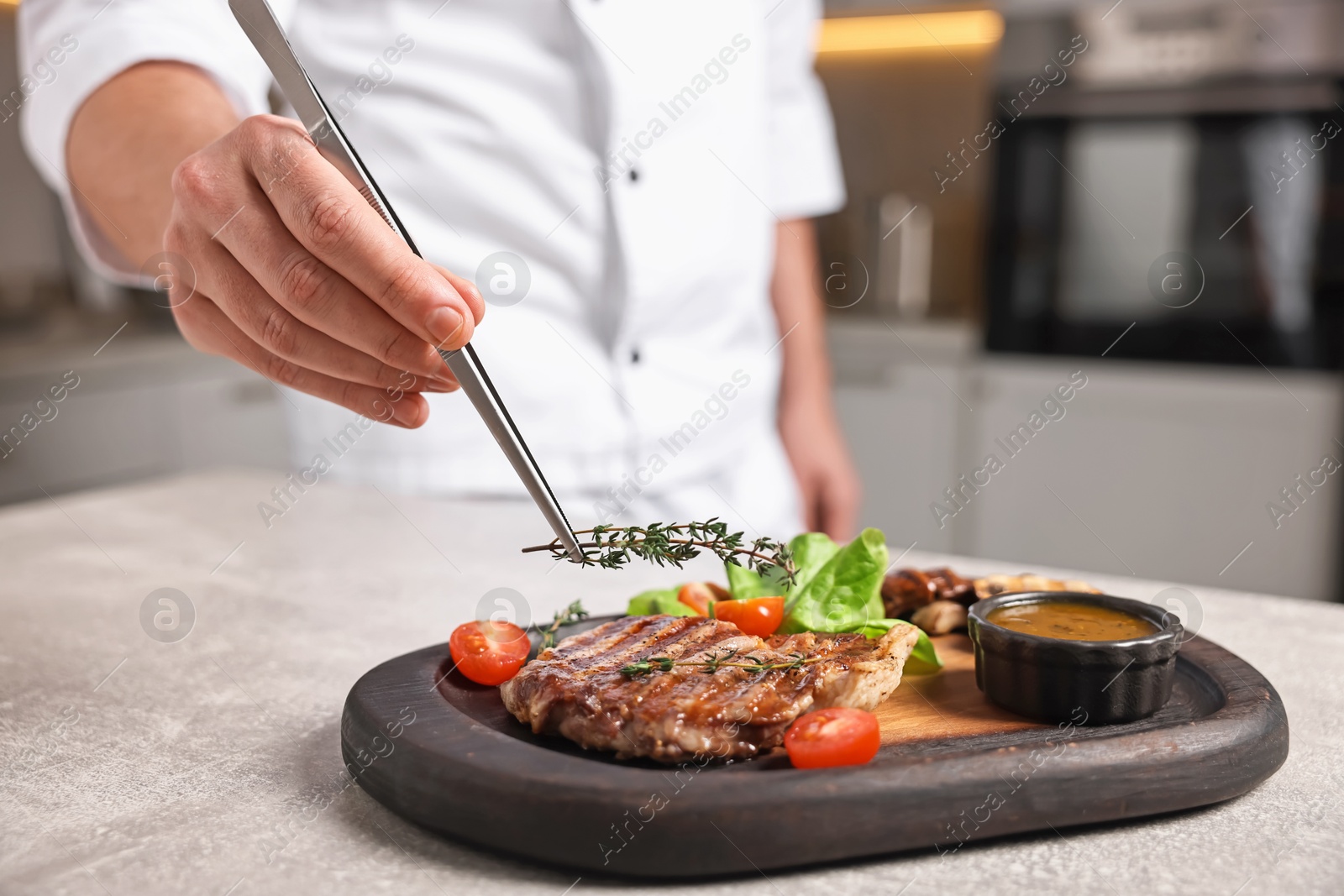 Photo of Professional chef serving dish at table indoors, closeup