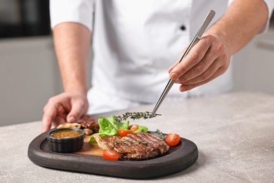 Photo of Professional chef serving dish at table indoors, closeup