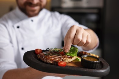 Professional chef serving delicious dish indoors, closeup