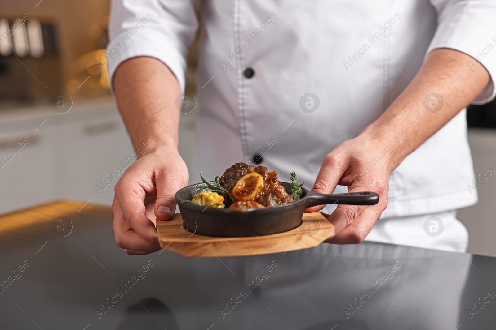 Photo of Professional chef serving dish at table indoors, closeup