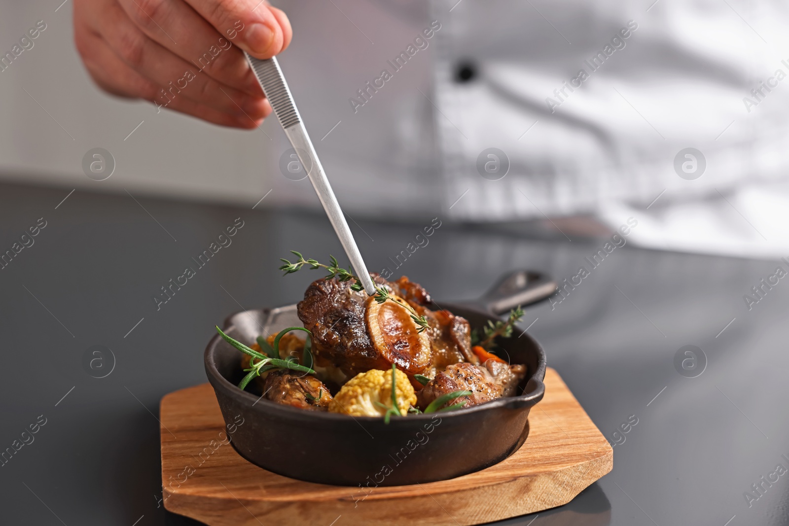 Photo of Professional chef serving dish at table indoors, closeup