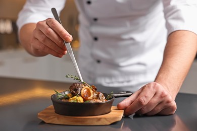 Photo of Professional chef serving dish at table indoors, closeup