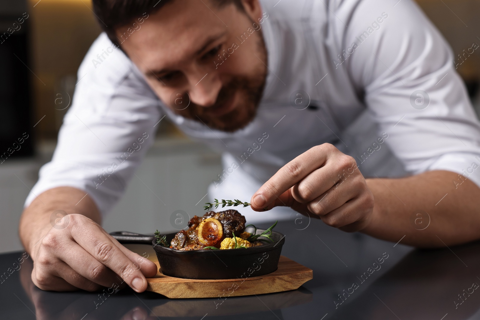 Photo of Professional chef serving dish at table indoors, selective focus