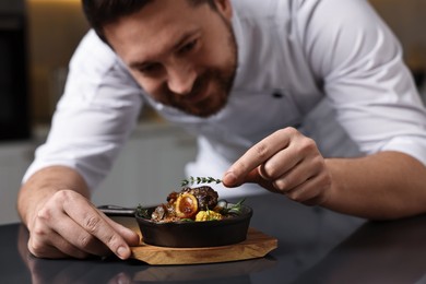 Photo of Professional chef serving dish at table indoors, selective focus