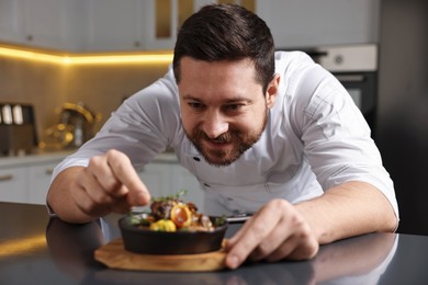 Photo of Professional chef serving dish at table indoors