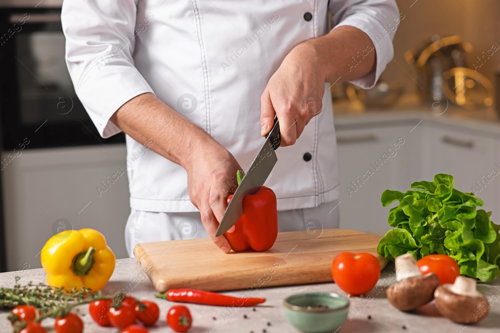 Photo of Professional chef cutting bell pepper at table in kitchen, closeup