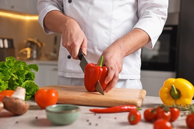 Photo of Professional chef cutting bell pepper at table in kitchen, closeup