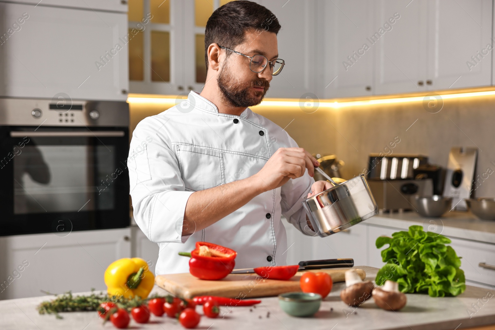 Photo of Professional chef cooking meal at table in kitchen