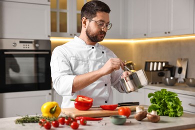 Photo of Professional chef cooking meal at table in kitchen