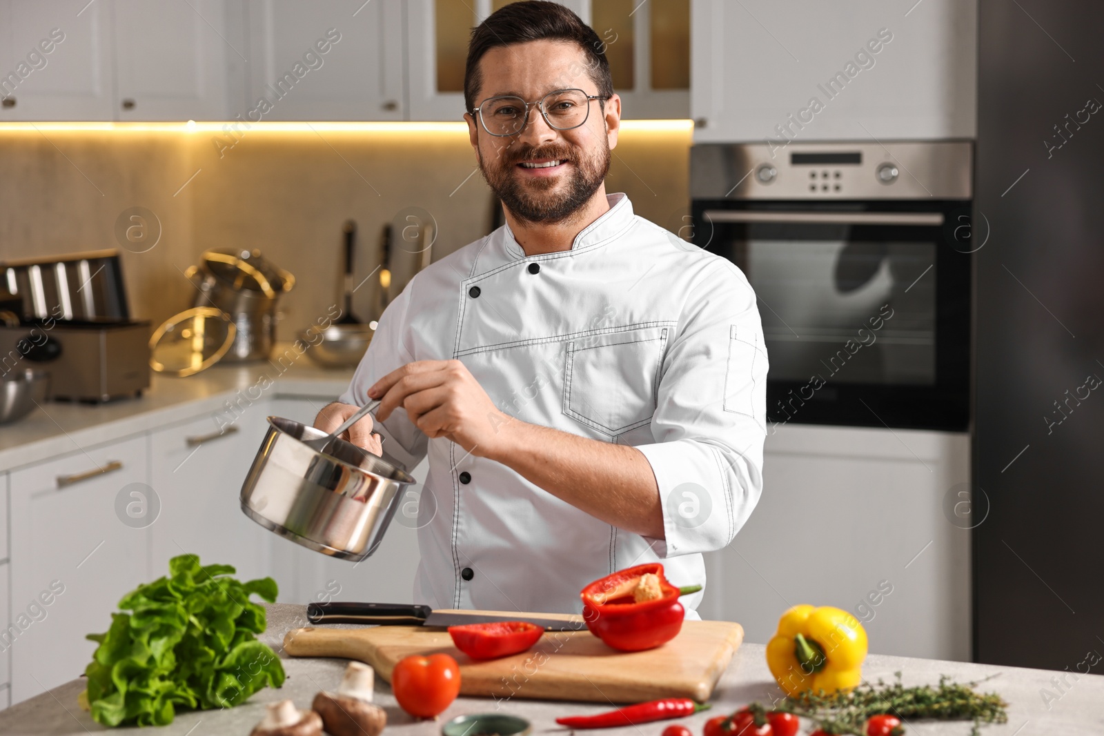 Photo of Professional chef cooking meal at table in kitchen