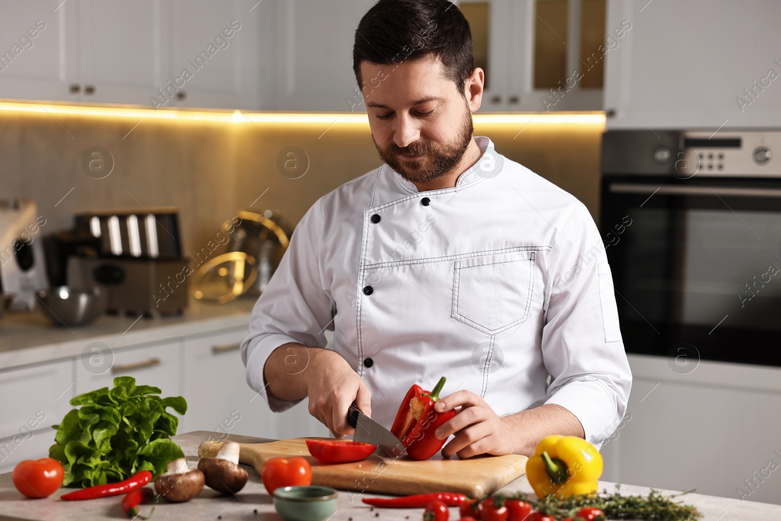 Photo of Professional chef cutting bell pepper at table in kitchen